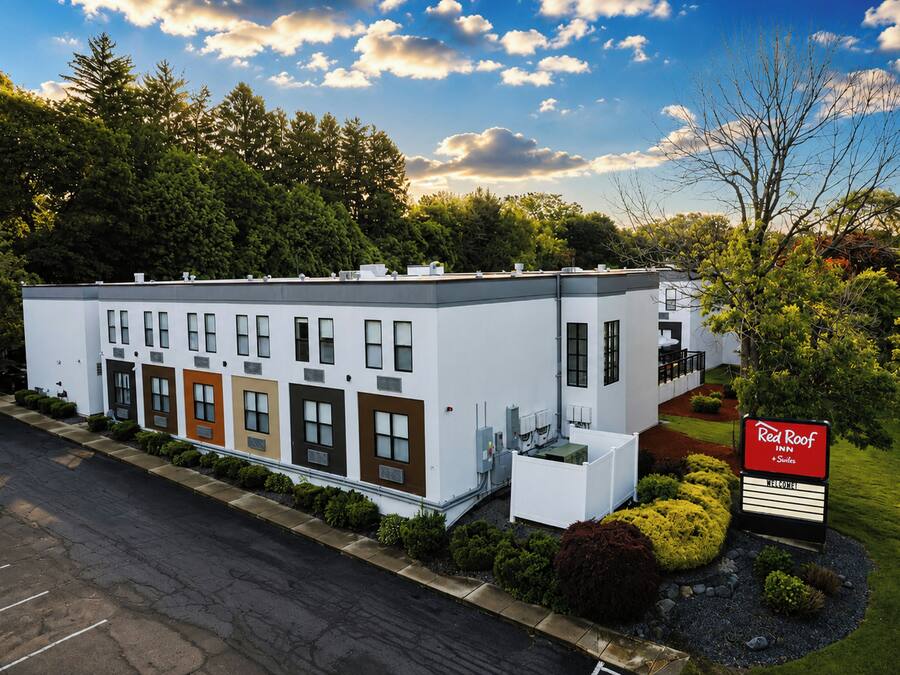 A modern building with multiple windows and a sign for Red Roof Suites.