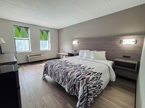 Habitación de hotel moderna con una cama grande, mesitas de noche, un escritorio y una ventana con persianas.