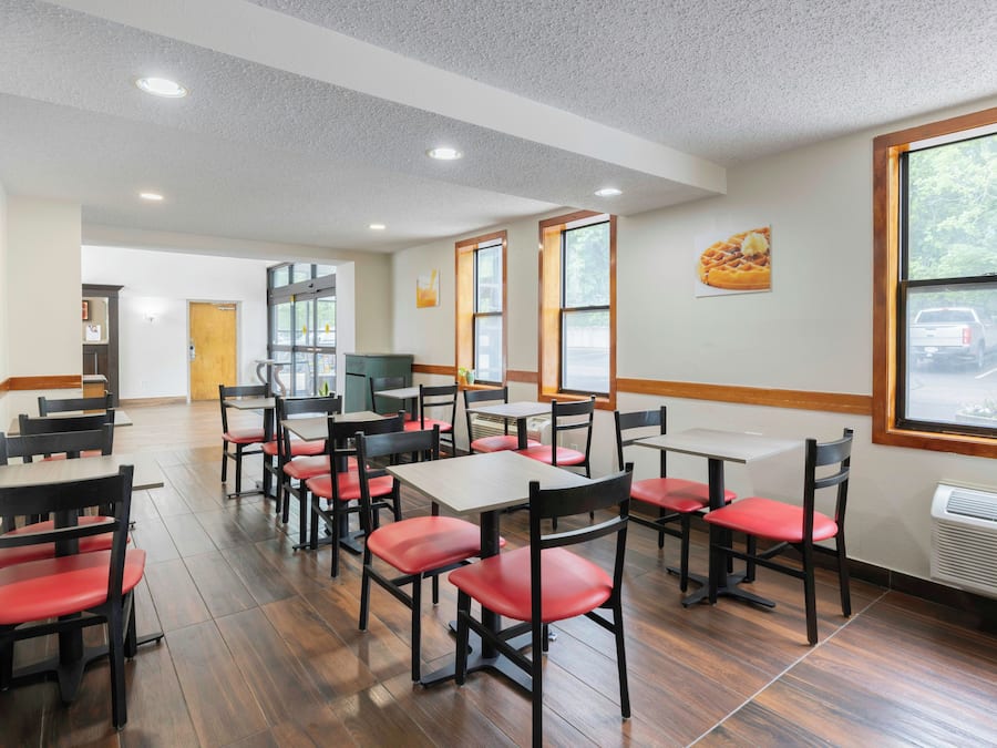 A dining area with multiple tables and chairs, a large window with a view, and a ceiling with recessed lighting.