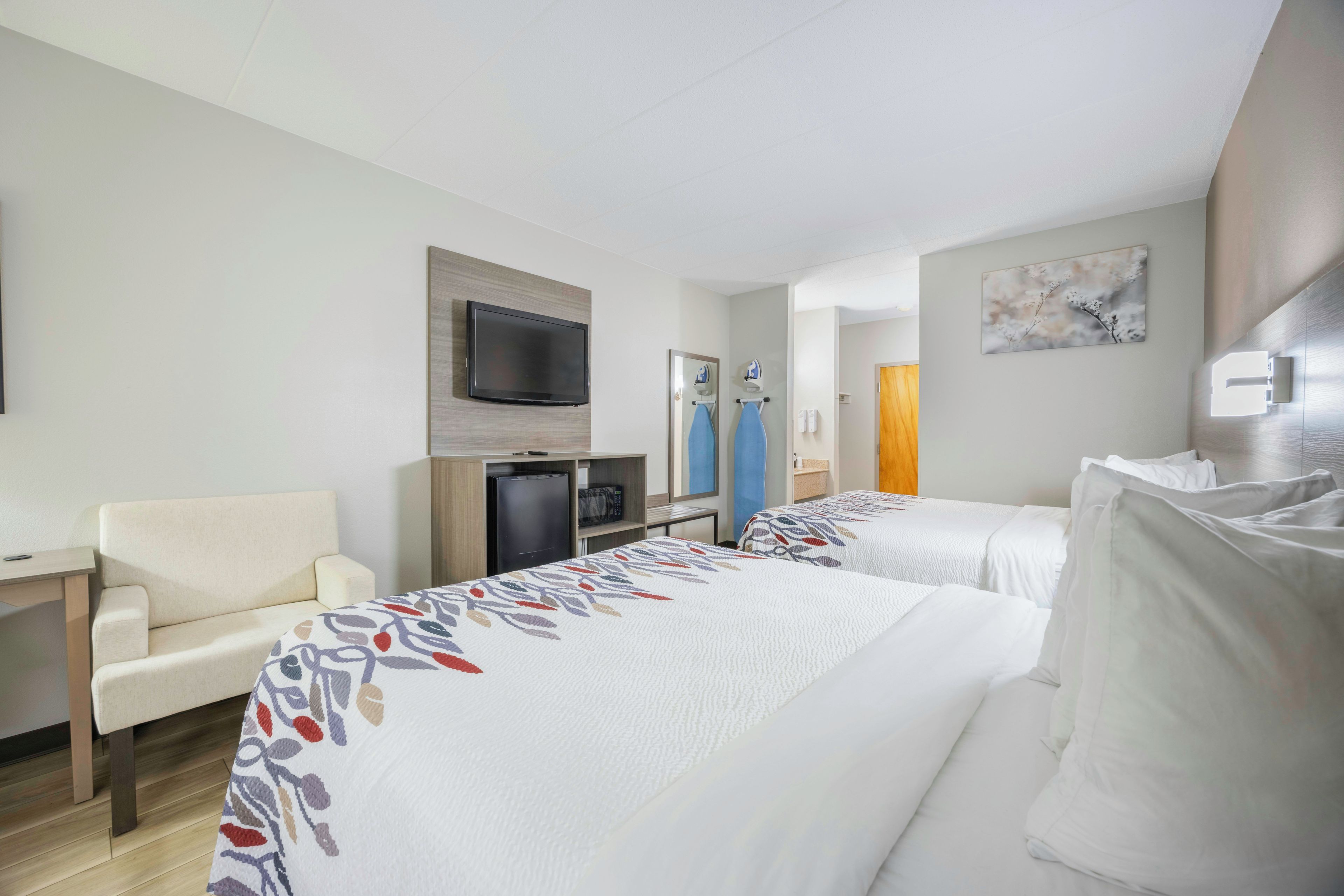 Habitación de hotel con dos camas, un escritorio, un televisor y un microondas.