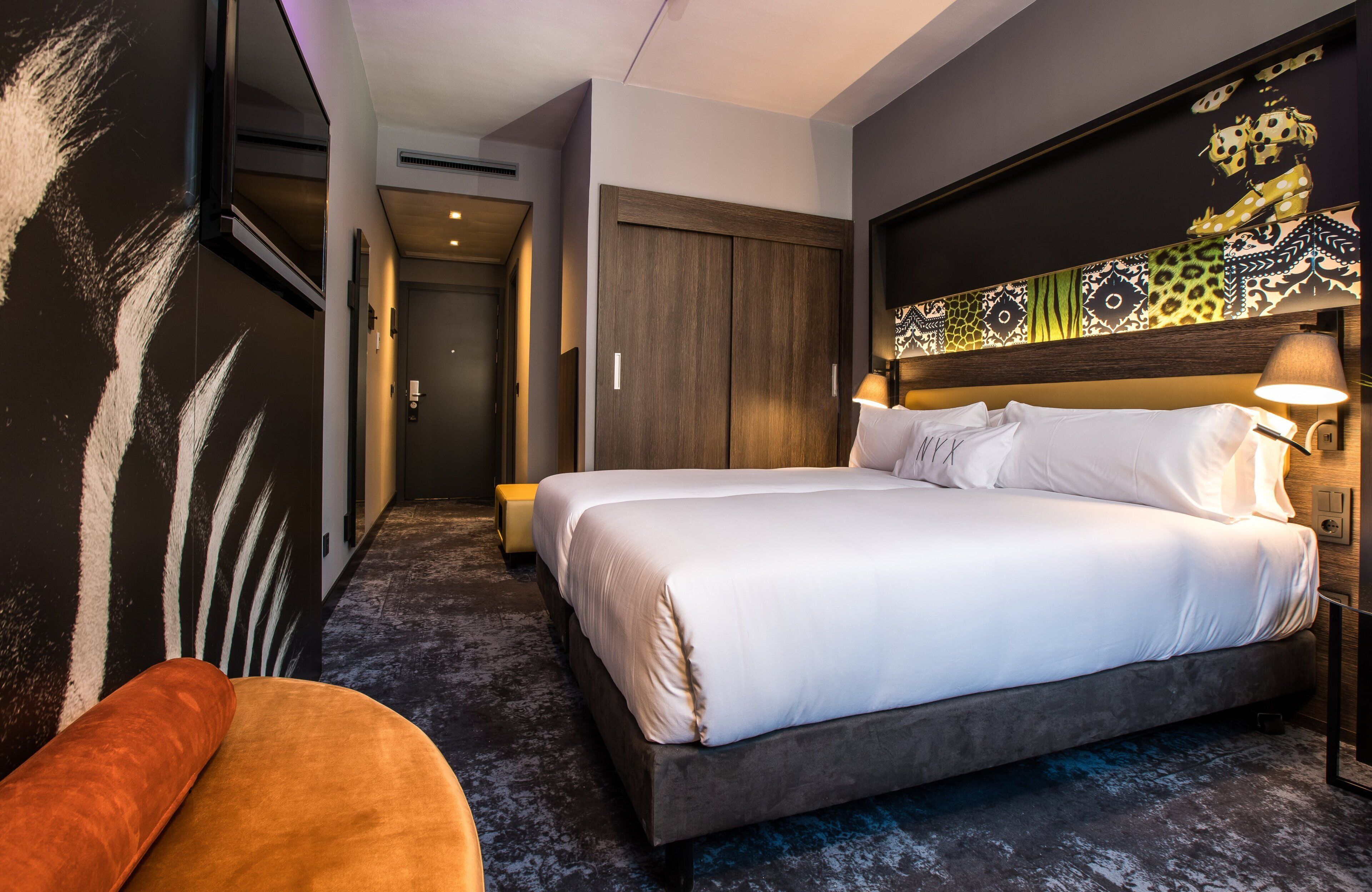 A hotel room with a large bed, a sofa, and a decorative wall.