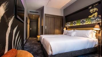 A hotel room with a large bed, a sofa, and a decorative wall.