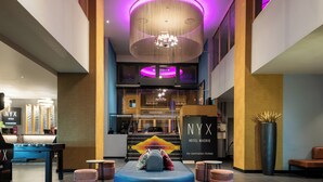 A hotel lobby with a pool table, seating area, and a reception desk.