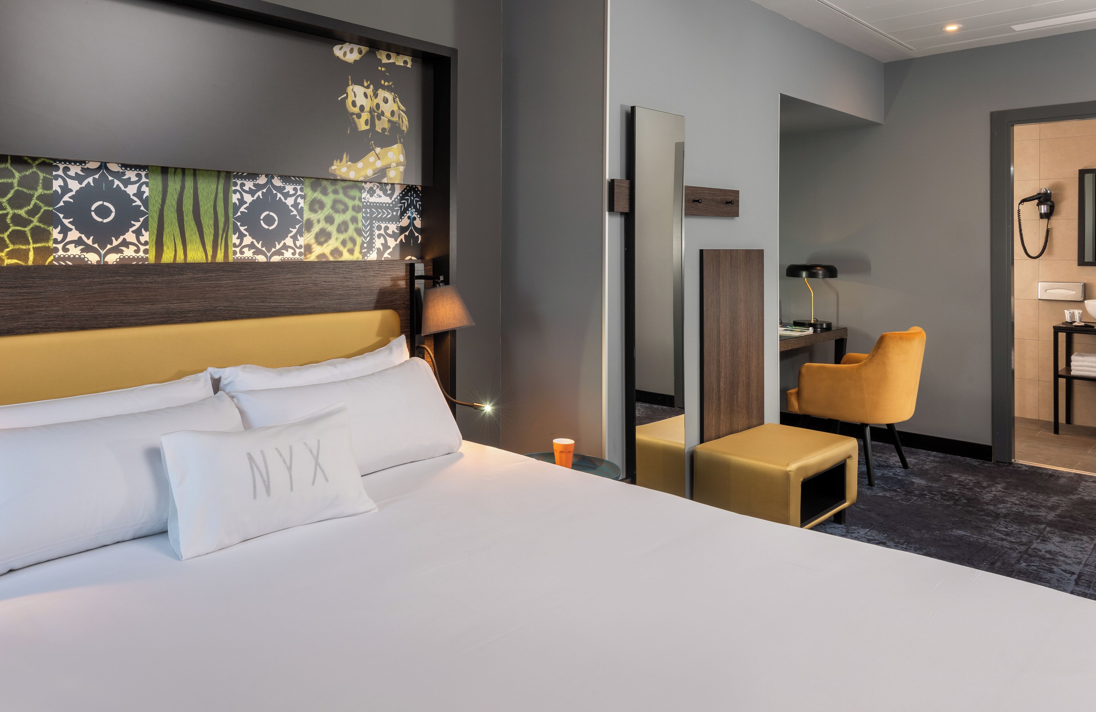 Habitació d'hotel amb un llit gran, una taula de treball, una cadira i un mirall.