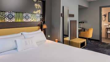 Habitació d'hotel amb un llit gran, una taula de treball, una cadira i un mirall.