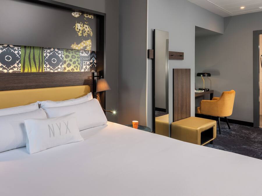 Habitació d'hotel amb un llit gran, una taula de treball, una cadira i un mirall.