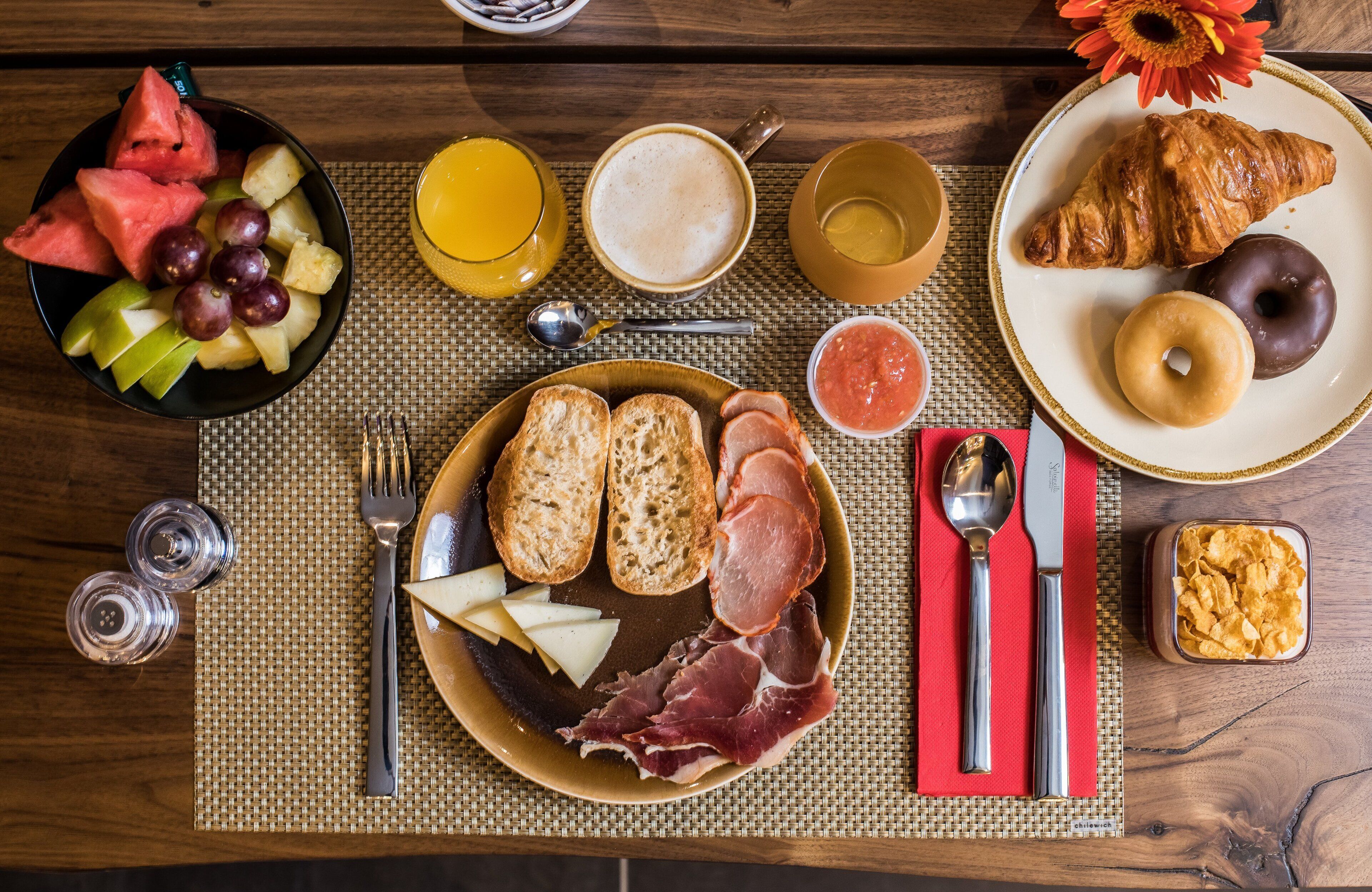 A breakfast setting with various food items and utensils on a table.