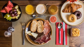 A breakfast setting with various food items and utensils on a table.