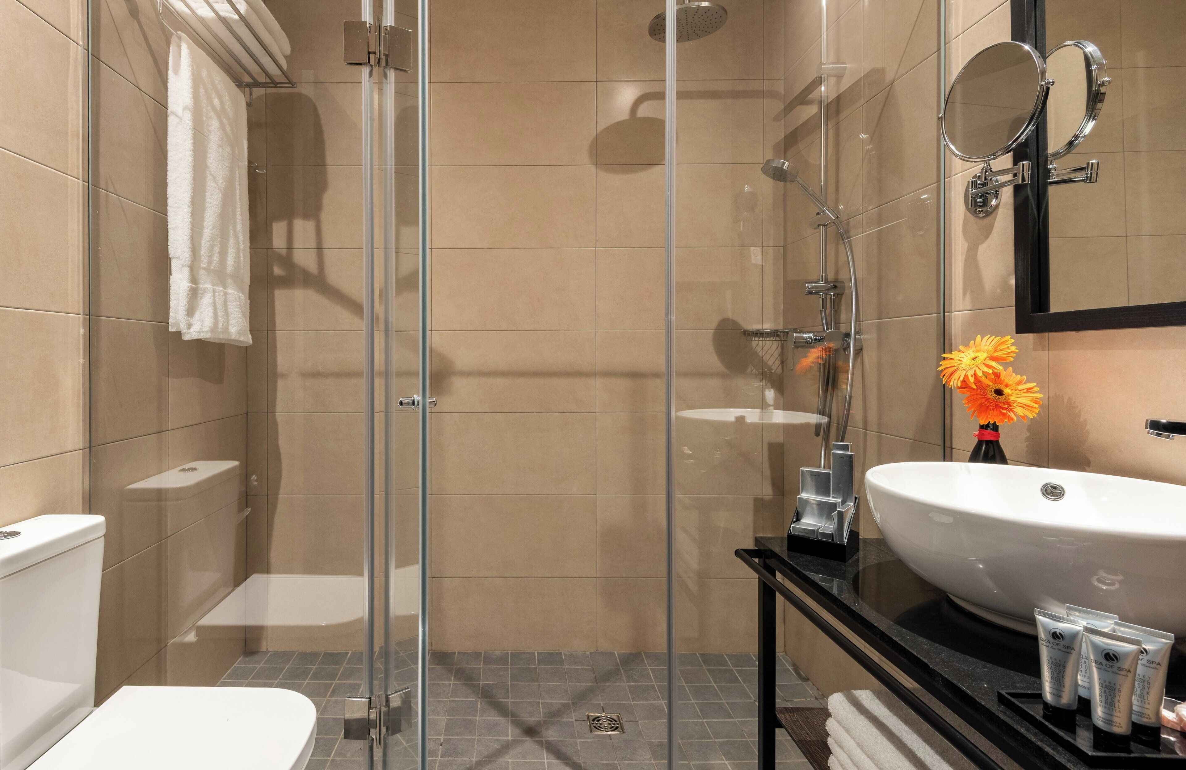 A modern bathroom with a glass-enclosed shower, a white sink, and a mirror above it.
