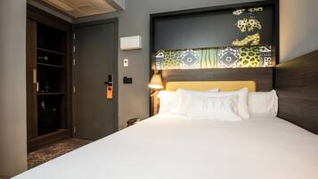 Una habitación de hotel con una cama, una mesita de noche, una lámpara, un armario y una puerta.