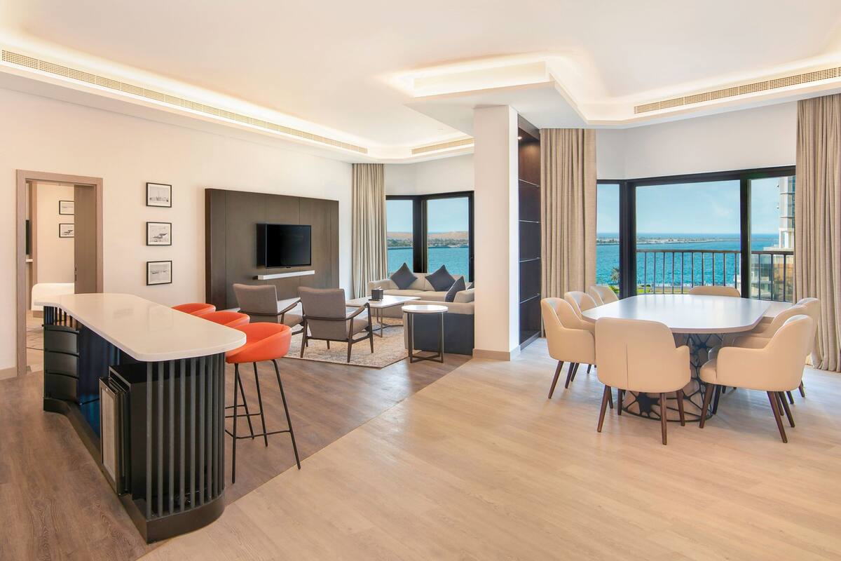Habitación de hotel moderna con comedor, televisión y vista al mar.