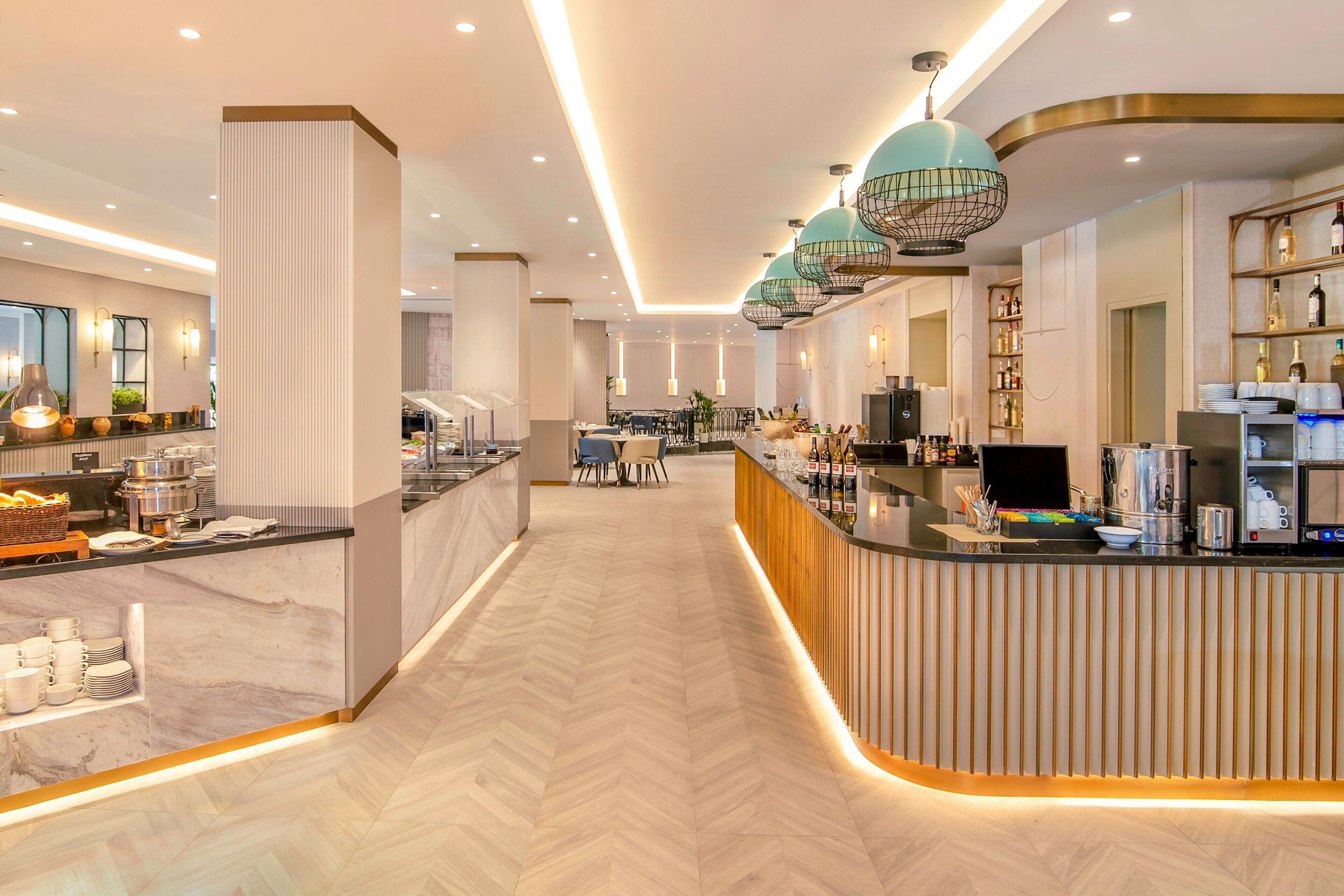 Un hall d’hôtel moderne comprenant un comptoir d’accueil, un espace buffet et des sièges.
