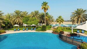 A pool area with lounge chairs and umbrellas, surrounded by palm trees. - Sheraton Abu Dhabi Hotel & Resort (Abu Dhabi)