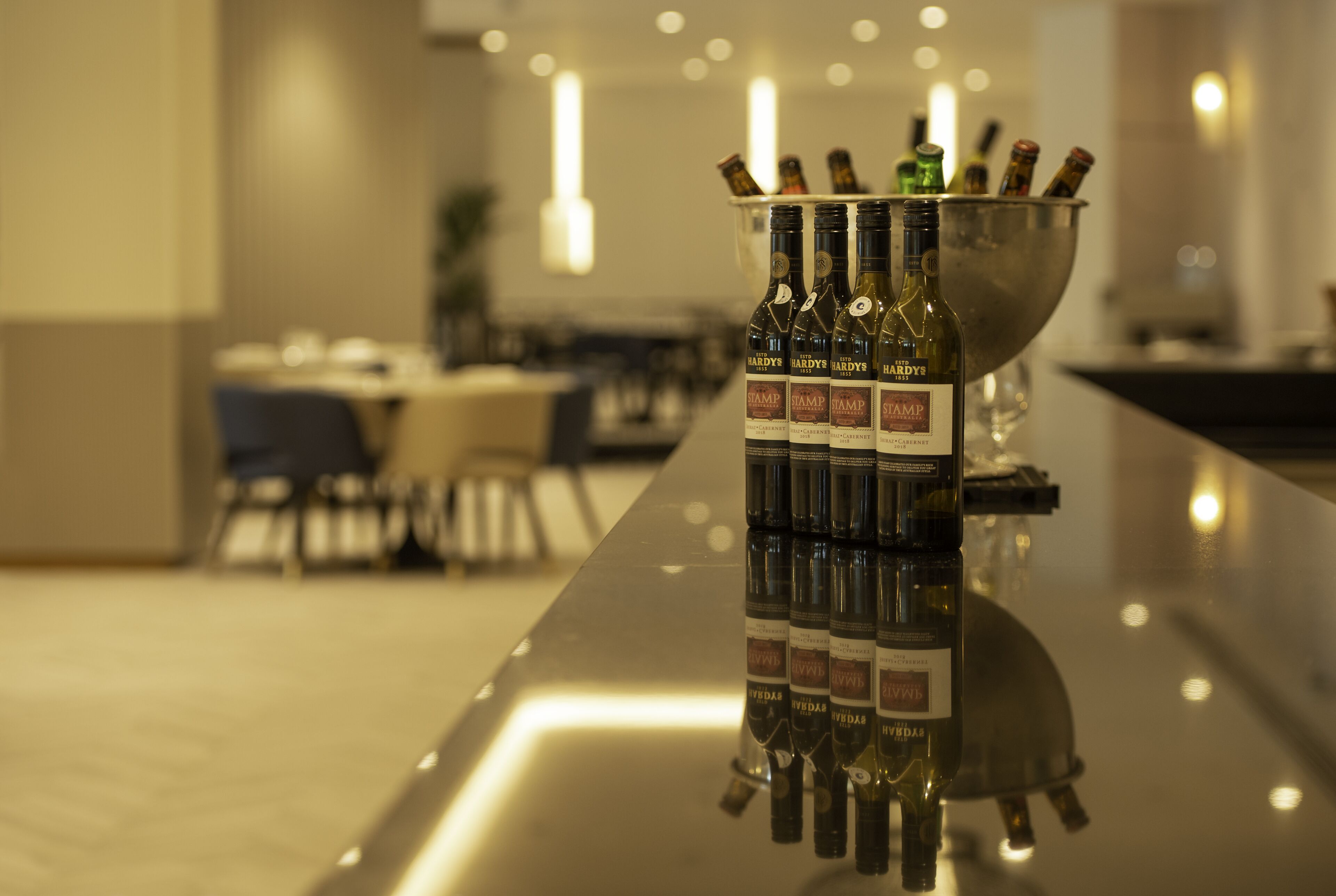 A bar area with a bottle holder containing multiple bottles of Hardys wine.