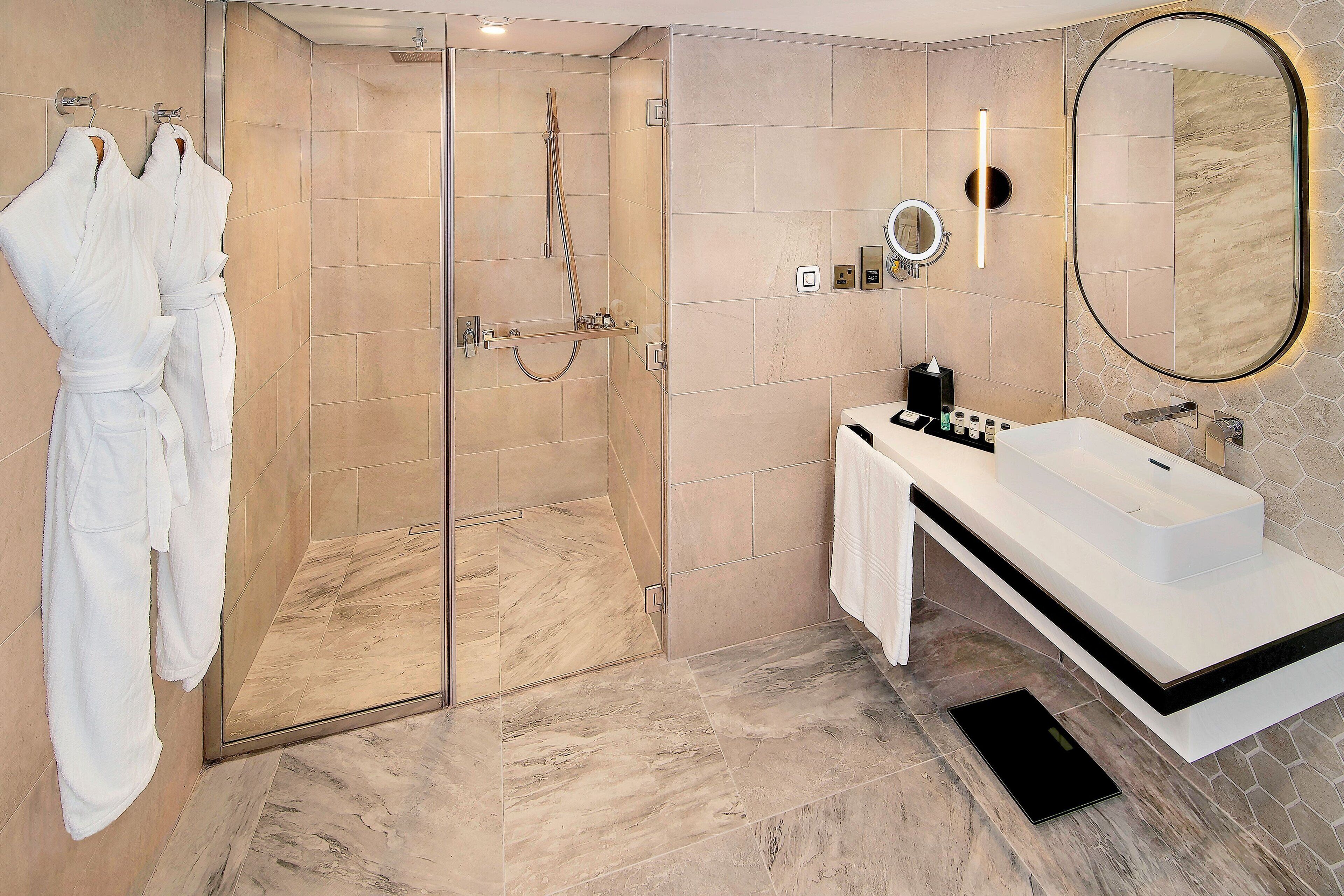Une salle de bain moderne avec une douche à parois de verre, un lavabo blanc et un grand miroir.