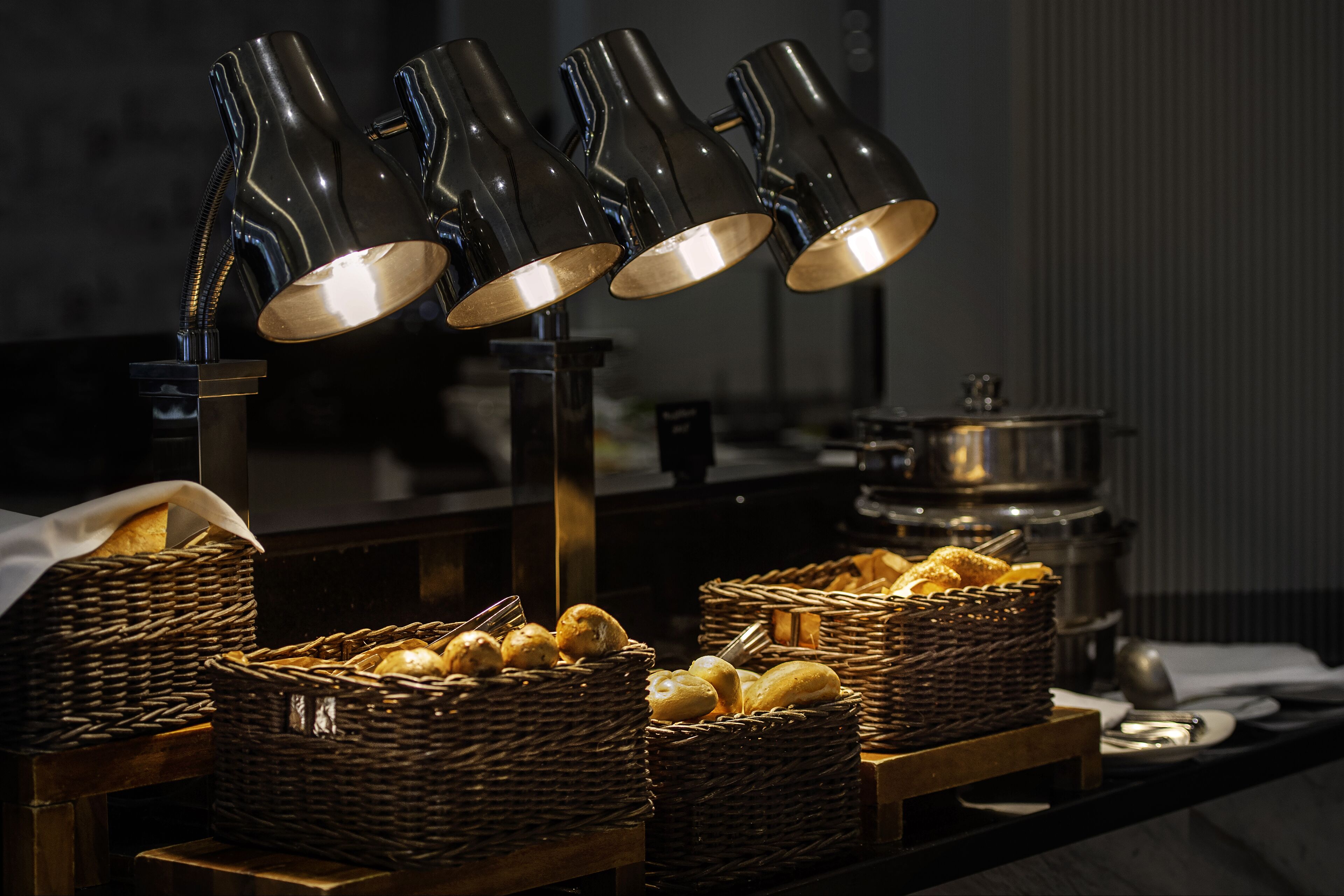 A buffet setup with wicker baskets of bread and a coffee station with multiple coffee dispensers.