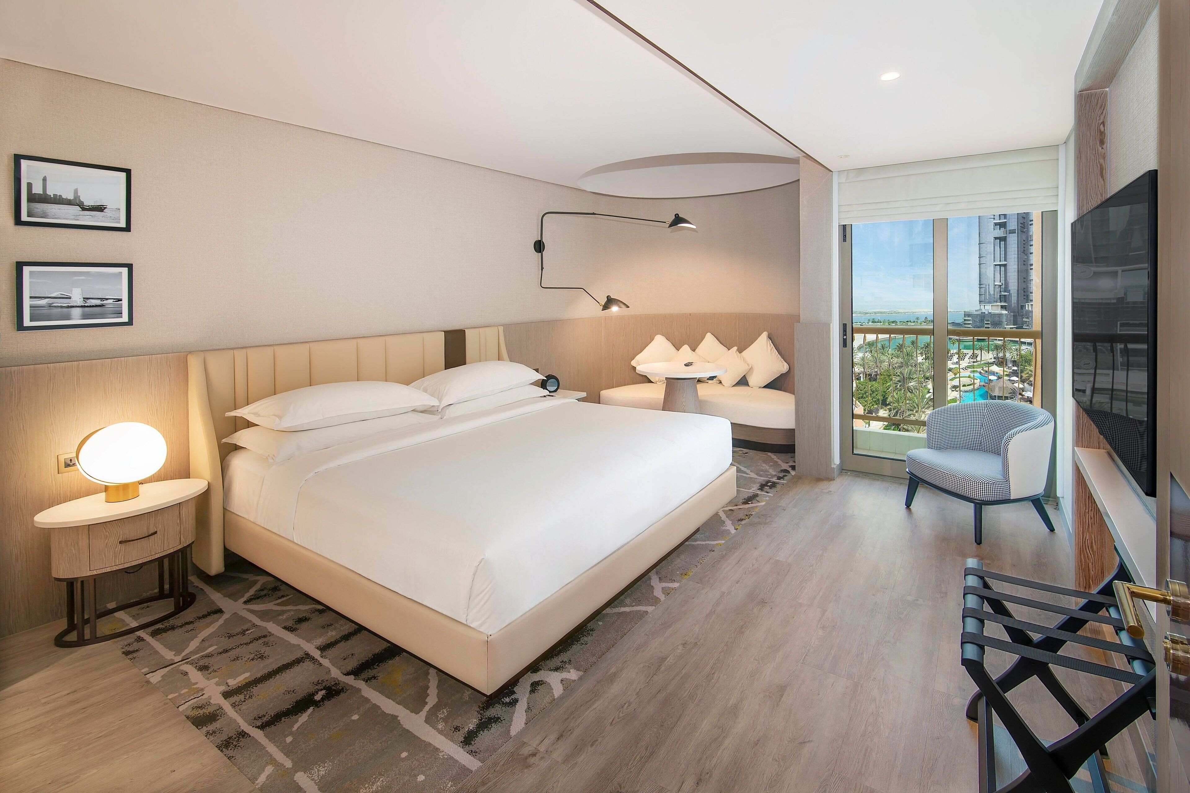 A modern hotel room with a large bed, bedside lamps, a desk, and a chair.