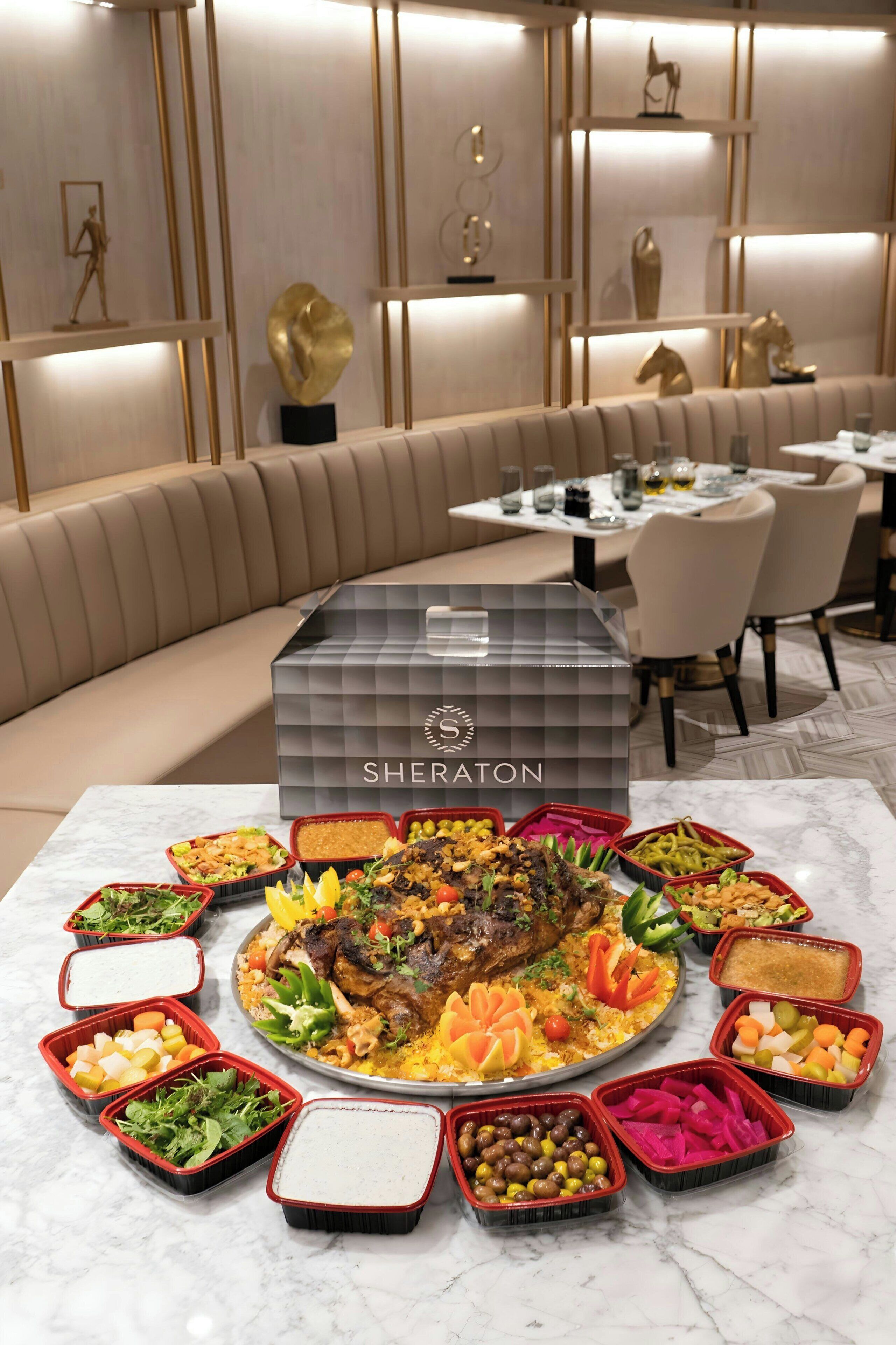 Ein luxuriöser Essbereich mit verschiedenen Speisen und dem Sheraton-Logo auf einem Tisch.