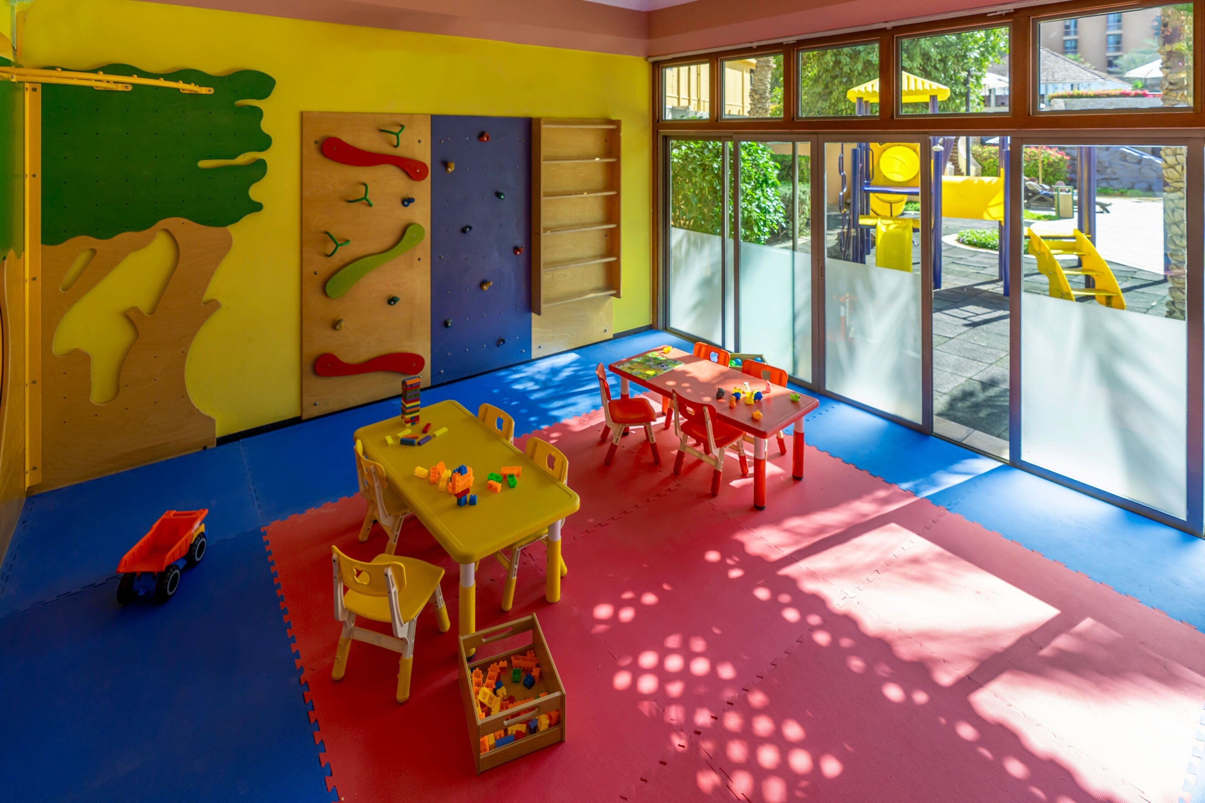 A brightly colored playroom with climbing walls, tables, and chairs.