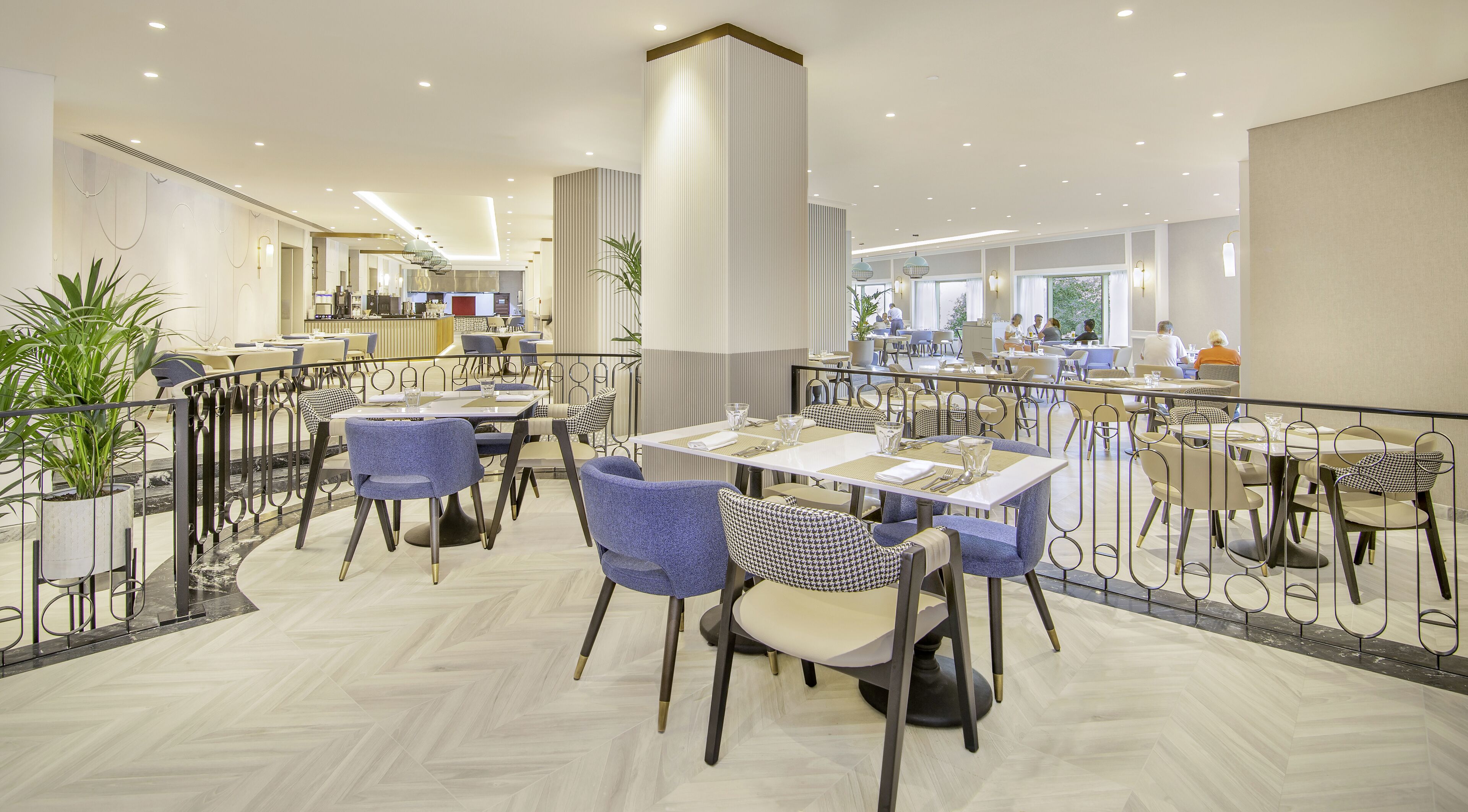 A spacious restaurant with multiple dining tables and chairs, a high ceiling with recessed lighting, and a modern interior design.
