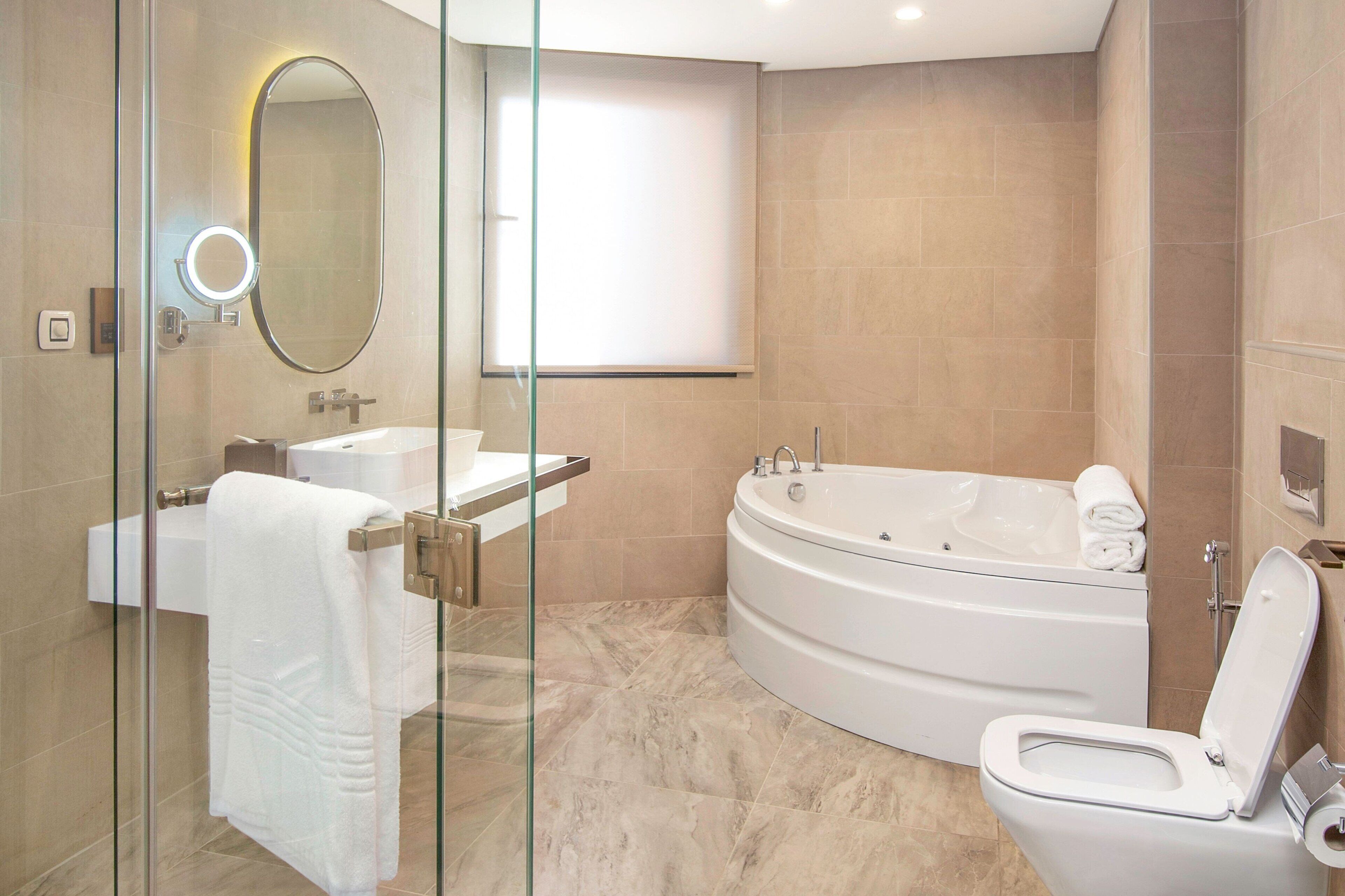 A modern bathroom with a glass-enclosed shower, a freestanding bathtub, a toilet, and a sink with a mirror.
