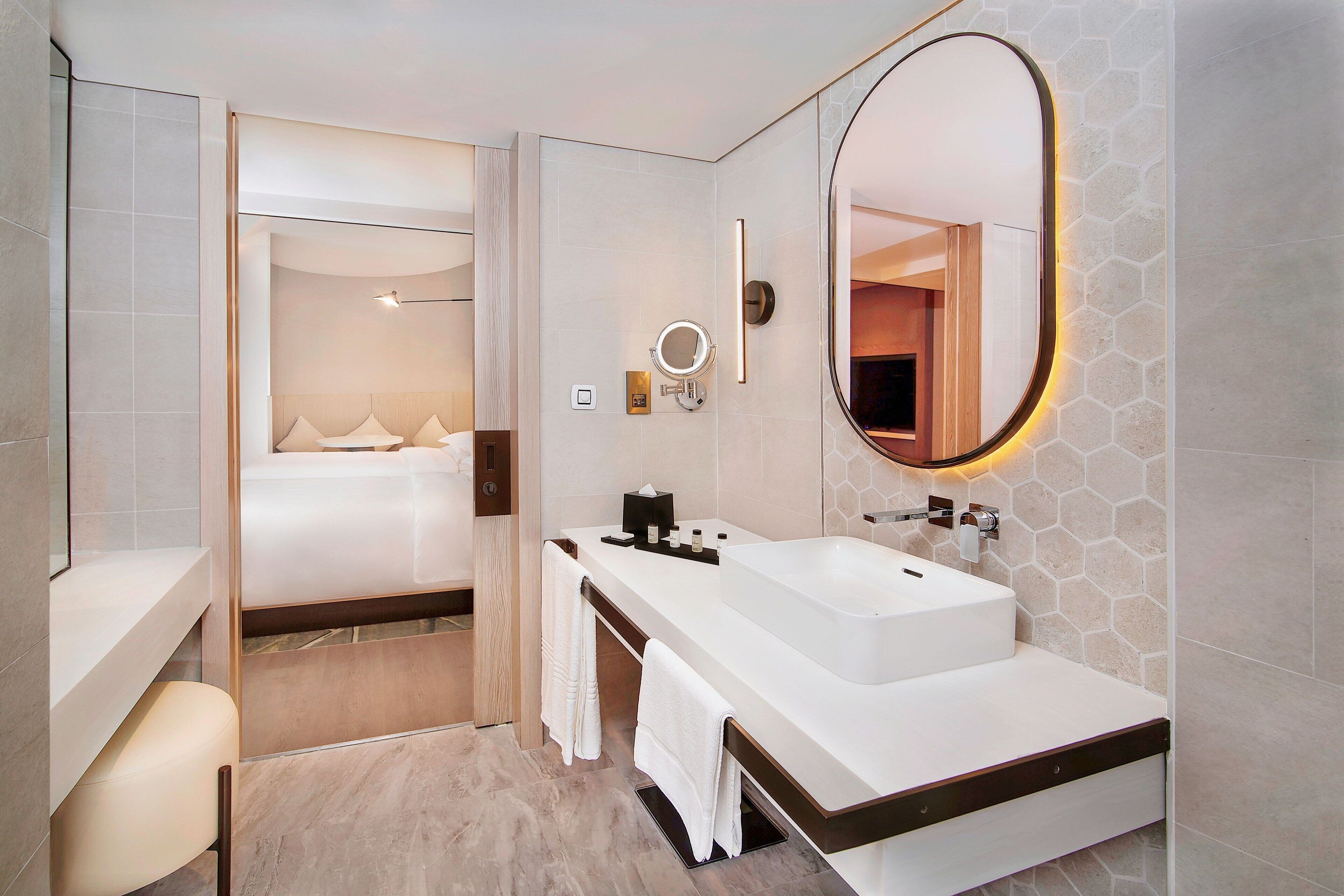 Un baño moderno con un lavamanos amplio, un espejo y un perchero para toallas.