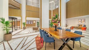 A spacious lobby with a large wooden table, blue chairs, and a floral centerpiece. - Sheraton Abu Dhabi Hotel & Resort (Abu Dhabi)