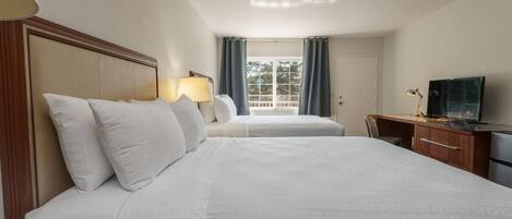 A hotel room with two beds, a desk, a television, and a window with curtains.