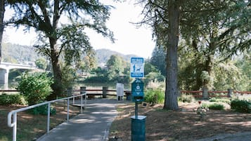 A park pathway with a pet waste station and a sign indicating pet waste disposal.