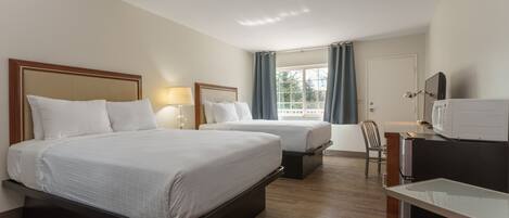 A hotel room with two beds, a desk, a chair, and a window with curtains.