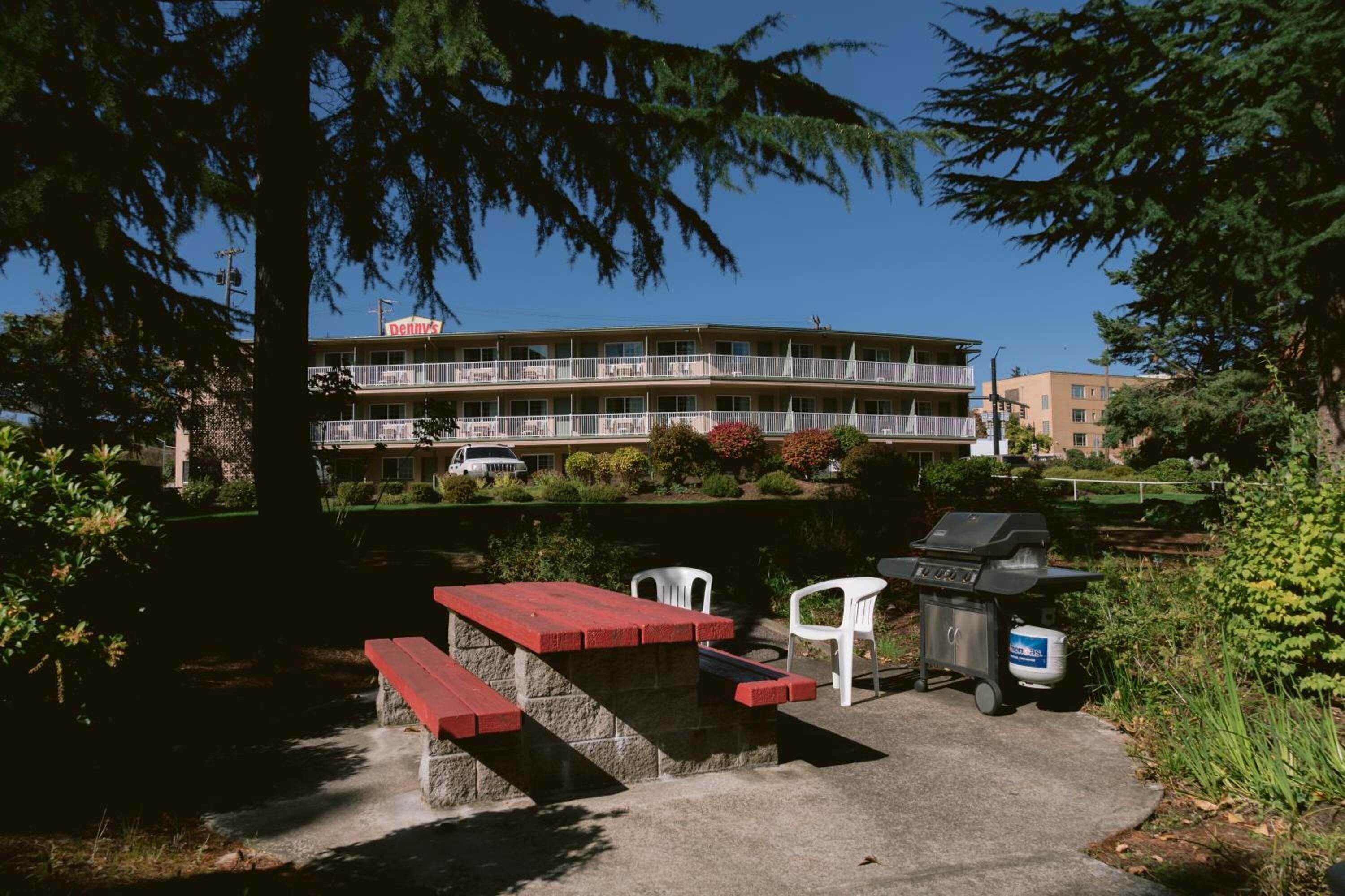 A motel with a barbecue area, outdoor seating, and a parking lot.