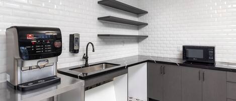 A modern kitchen with a coffee machine, a microwave, and a sink.