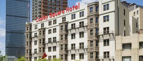 A hotel with a classic facade, multiple windows, and a prominent sign.