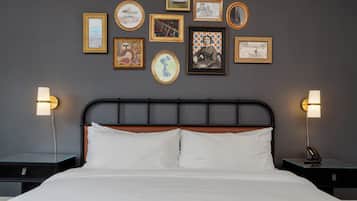 A neatly made bed with white linens, a wooden headboard, and two bedside tables with lamps.