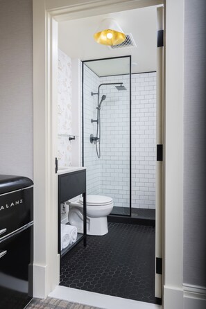 A modern bathroom with a glass-enclosed shower, white toilet, and a black vanity. - Copley Square Hotel, a FOUND Hotel (Boston)