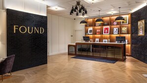 A reception area with a black wall, wooden desk, and pendant lighting. - Copley Square Hotel, a FOUND Hotel (Boston)
