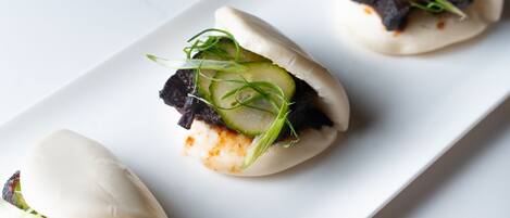 Three dumplings with toppings on a white plate.