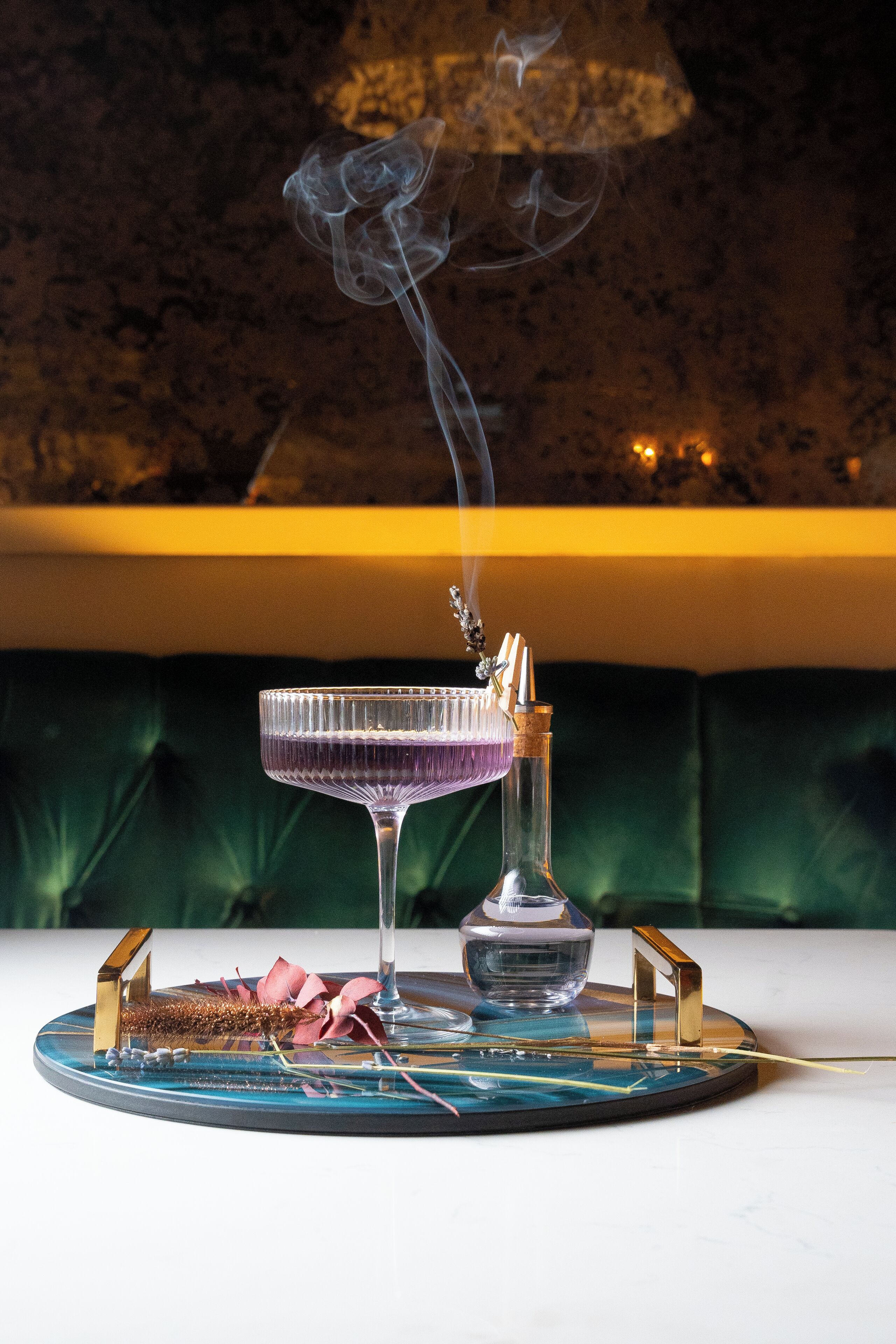 A cocktail glass on a coaster with a bottle and a hookah.