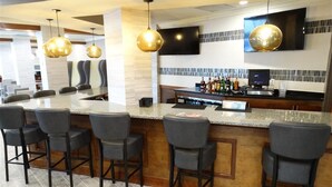 A bar area with a counter, bar stools, and a television mounted on the wall.