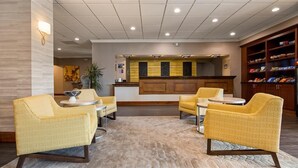 A lobby with yellow patterned chairs, a reception desk, and a snack bar.