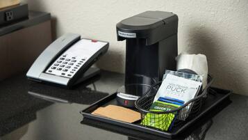 Una macchina per caffè, un telefono e un vassoio con capsule di caffè e fazzoletti su un bancone di un albergo.