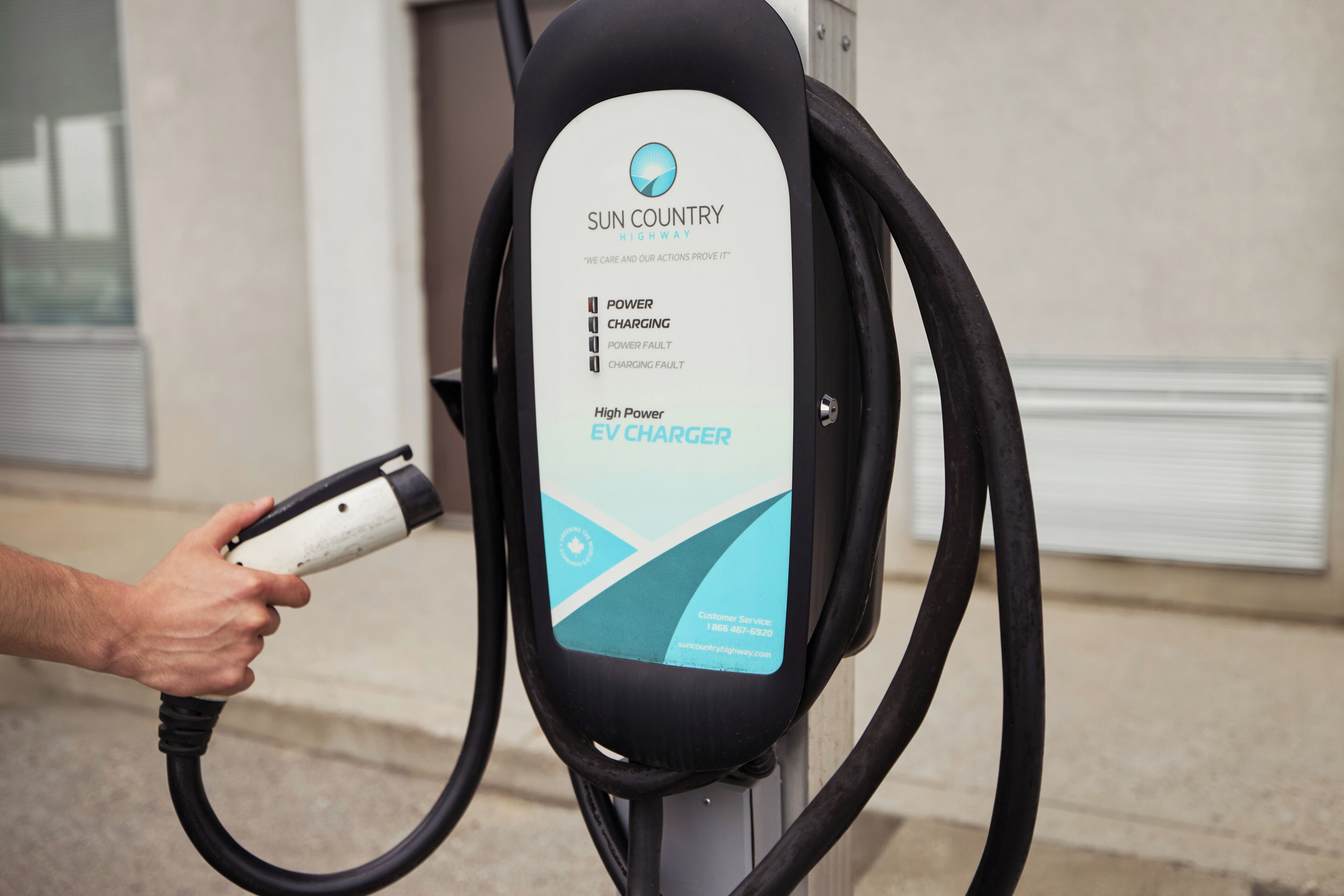 A person plugging an EV charger into a charging station.