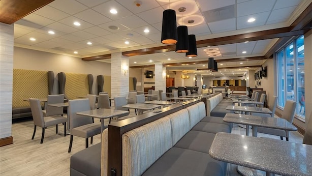 A modern restaurant with a long counter, booths, and high ceilings with recessed lighting.