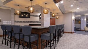 A bar area with a long counter and multiple bar stools.