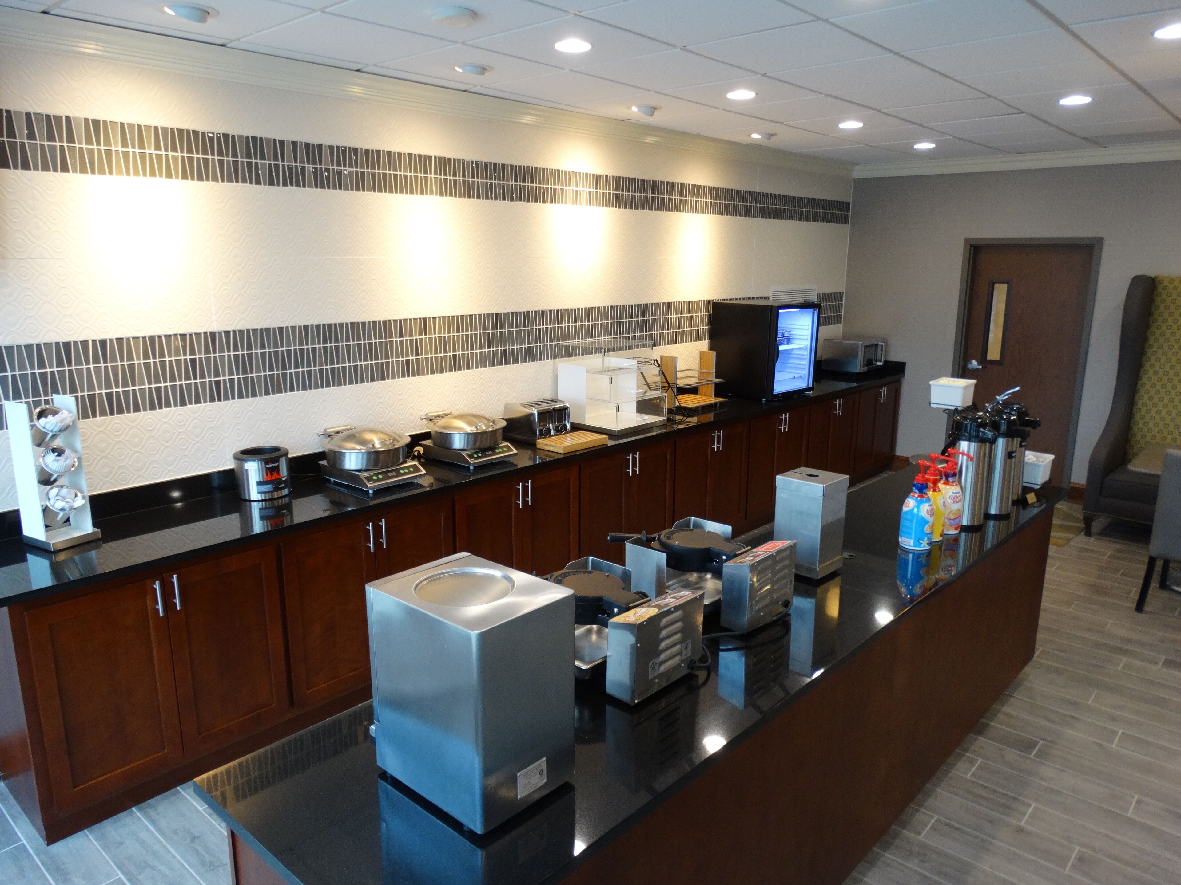 A modern kitchen with a long counter, equipped with various appliances and food dispensers.