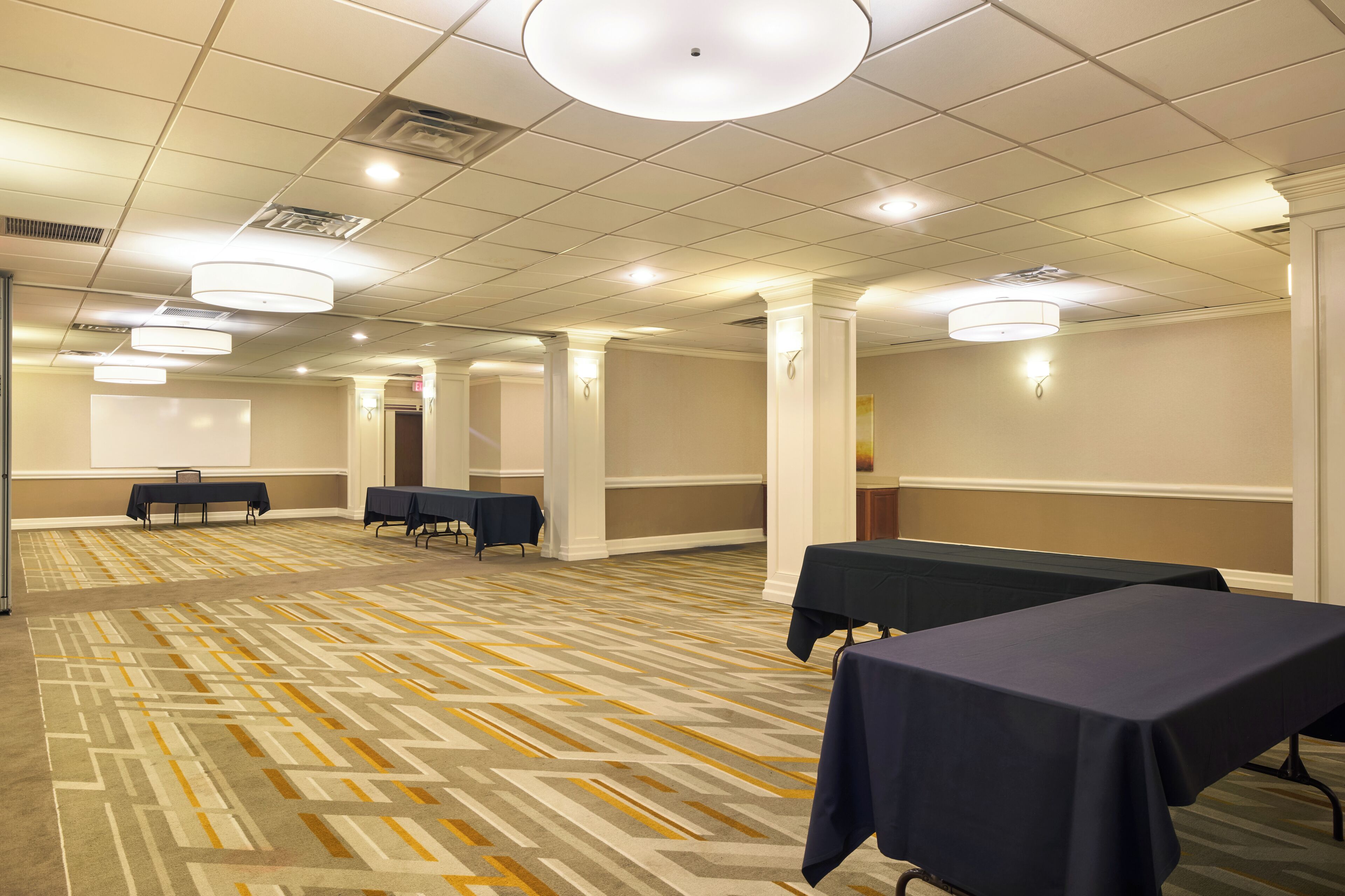 Un salón de conferencias con mesas, sillas y una pantalla para proyector.