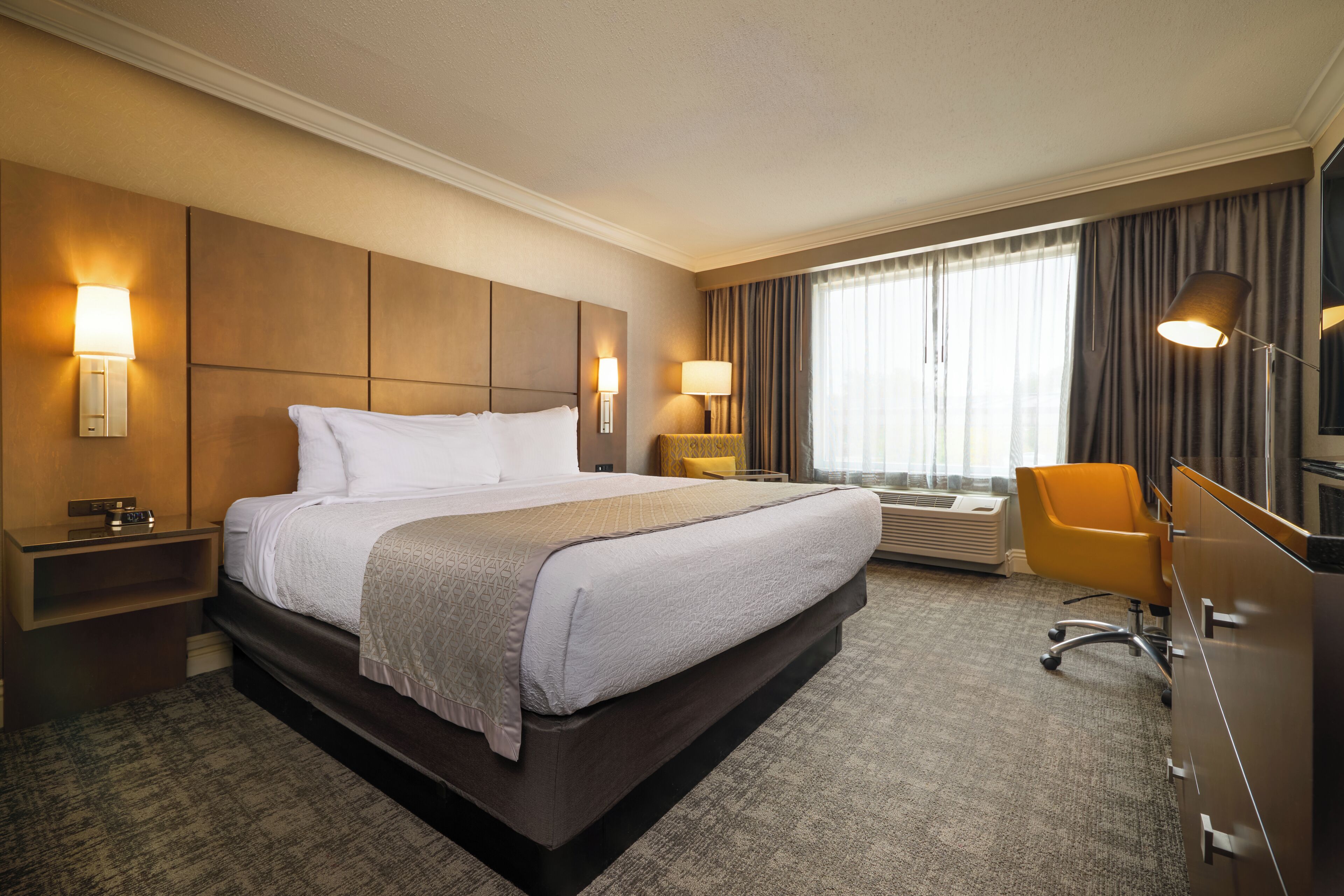 Une chambre d’hôtel avec un grand lit, des lampes de chevet, un bureau et une chaise.