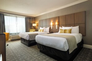Een hotelkamer met twee bedden, een bureau en een stoel.