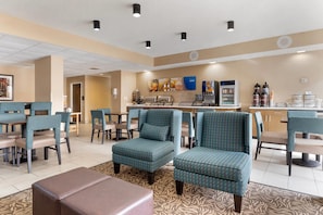 A hotel lobby with seating areas, a coffee station, and a counter.