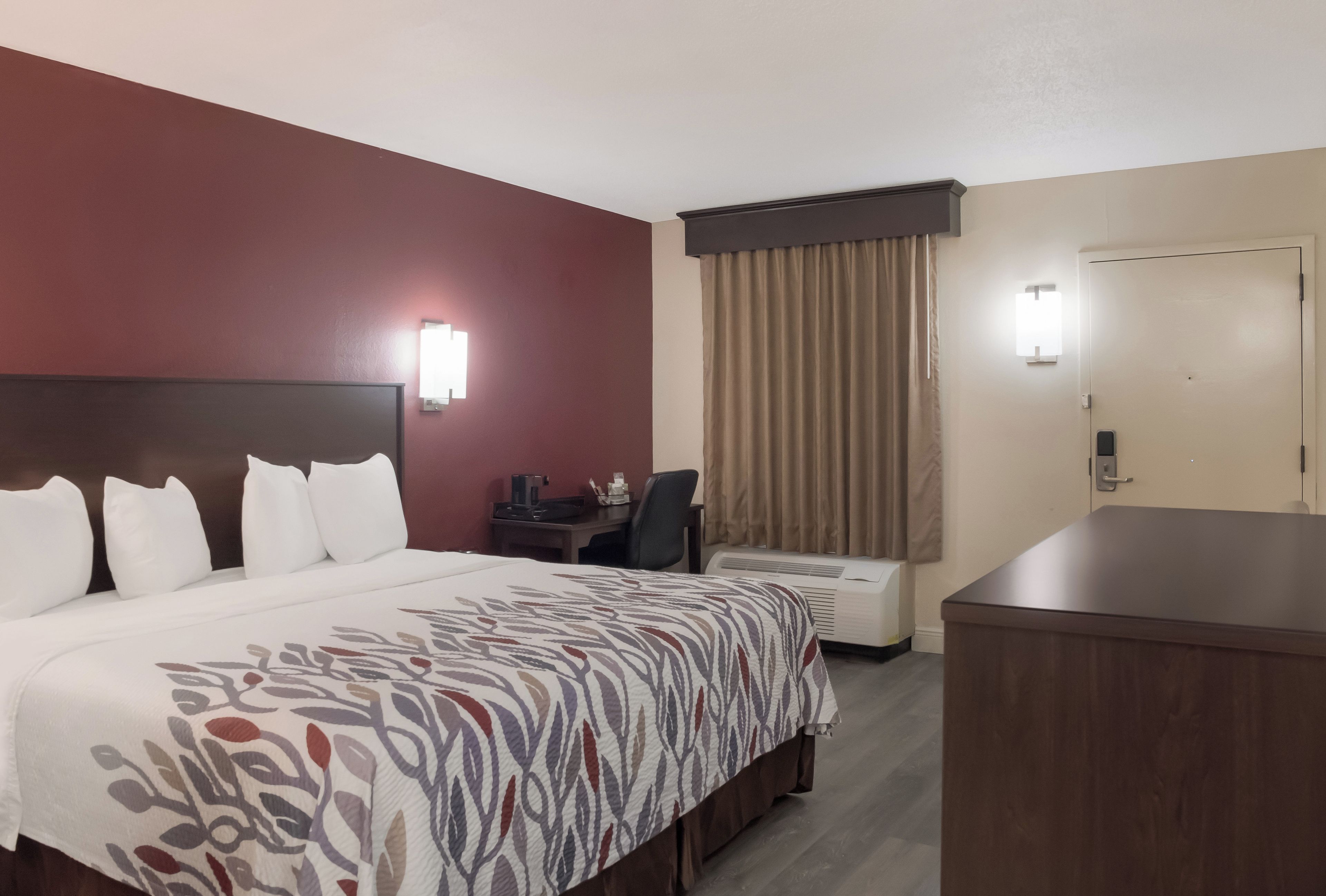 Une chambre d’hôtel avec un grand lit, un bureau, une chaise et un appareil de climatisation.
